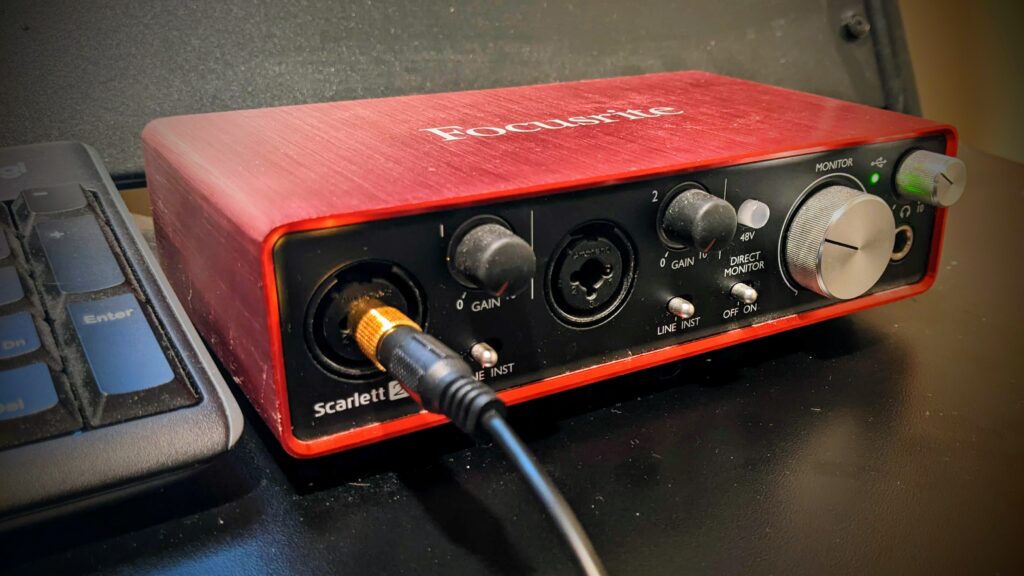 A Focusrite Scarlett 2i2 audio interface receiving an instrument cable.